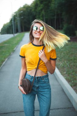 Parkta yürüyen genç şık neşeli kadın 