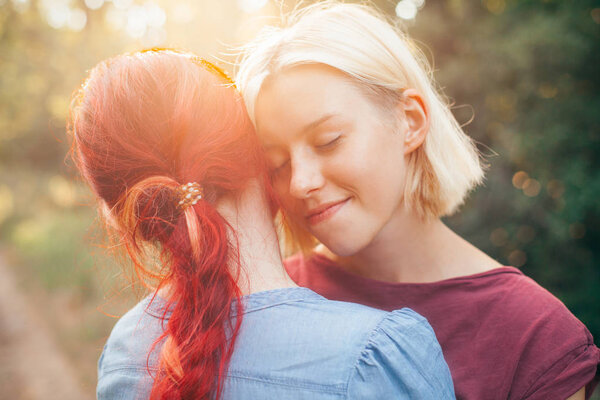 Two young females hugging in forest. Best friends. Close up