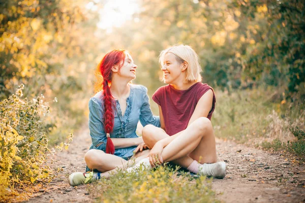 Dos Mujeres Jóvenes Sentadas Carretera Bosque Riendo —  Fotos de Stock