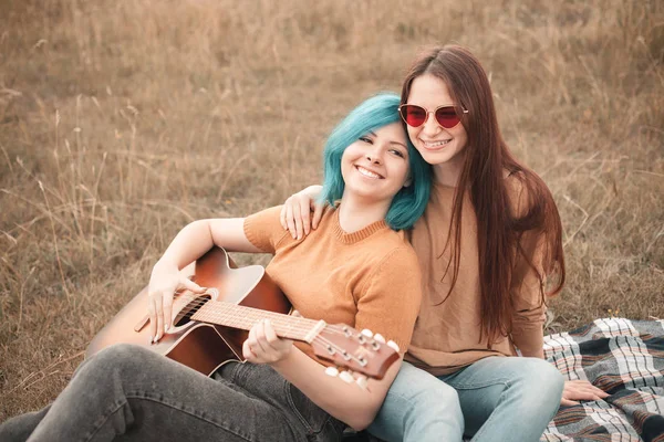 Две Молодые Женщины Лежат Поле Играют Гитаре Лучшие Друзья — стоковое фото