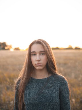 Calm young woman standing outdoors at evening