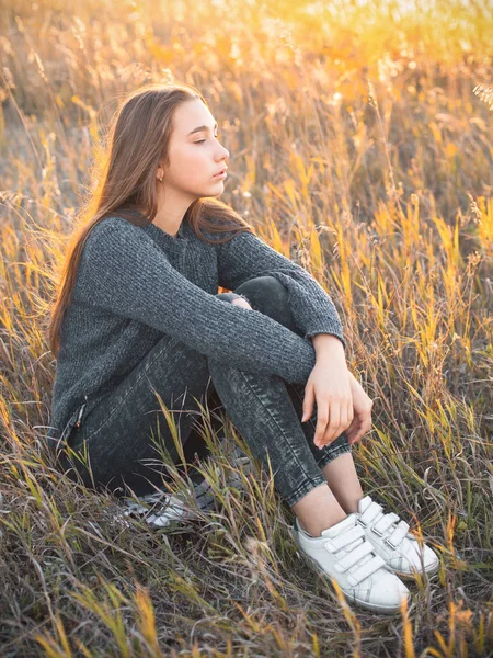 Piękna Młoda Kobieta Siedzi Wysokiej Trawie Zachodzie Słońca — Zdjęcie stockowe