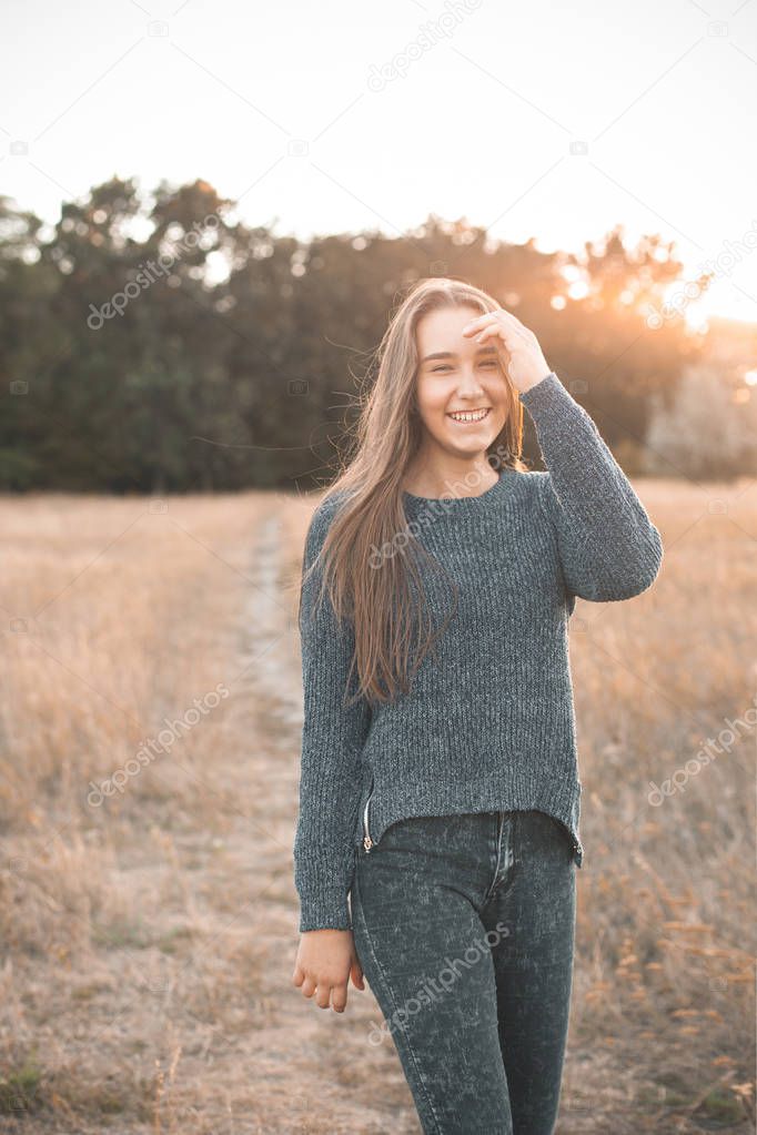 Beautiful  young woman walking on the field and smiling