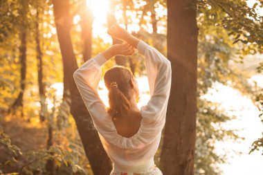 Genç kadın sonbahar ormanda günbatımında poz.