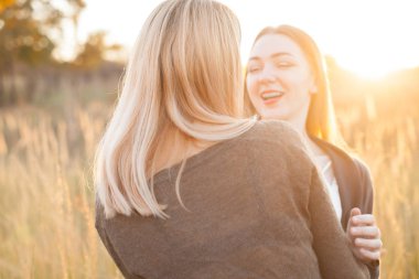 Eğlenceli açık havada günbatımında iki neşeli genç kadın.