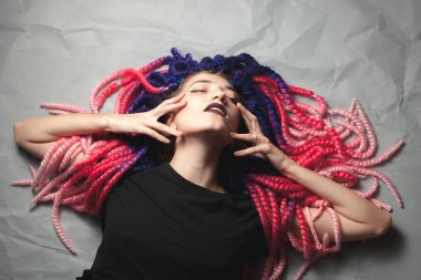 Gri arka plan üzerinde olağandışı saç kesimi olan tutkulu genç kadın