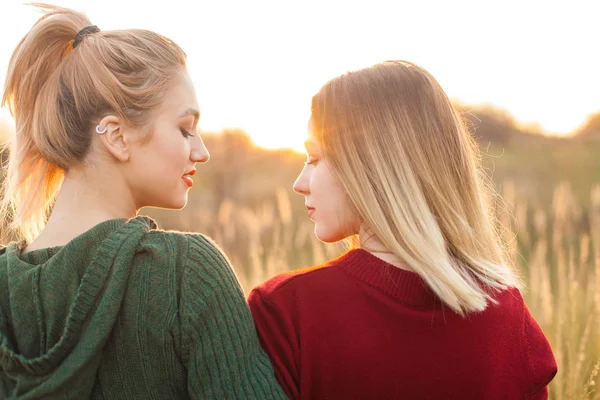 日落时 两个开朗的年轻女子站在地里 最好的朋友 — 图库照片