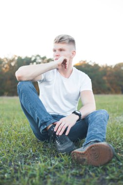 yakışıklı adam çimlere oturup