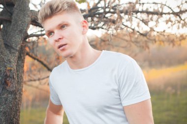 Gün batımında ağacın yanında duran genç adam