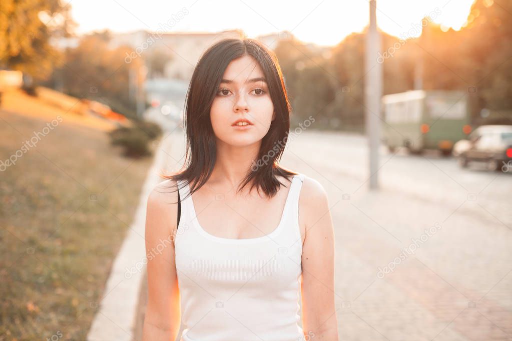 Beautiful young woman walking on the street at sunset