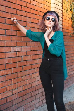 Moda kadın tuğla duvar yakınında duruyor