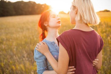 İki güzel genç kadın gün batımında açık havada sarılıyor. En iyi dostlar