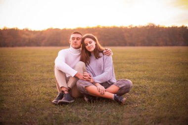 gün batımında çimlerde oturan genç Çift