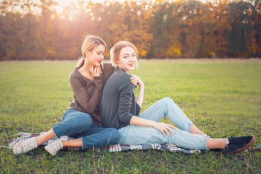 Çim üzerinde oturan iki genç kadın.