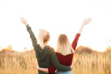 İki genç kadın sahada ayakta ve elleri yükseliyor. En iyi dostlar