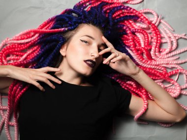 Güzel genç kadın, sıradışı saç kesimi yerde yatıyor