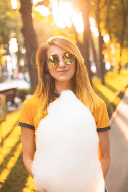 Pamuk şeker ile genç kadın parkta duruyor