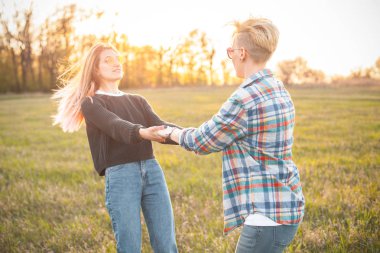 İki güzel genç kadın güneş ışığında açık havada eğleniyor.
