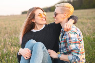 Gün batımında yeşil alanda oturan iki çekici genç kadın.