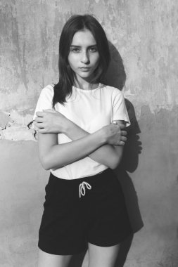 Duvara yakın duran çekici genç kadın. Siyah beyaz