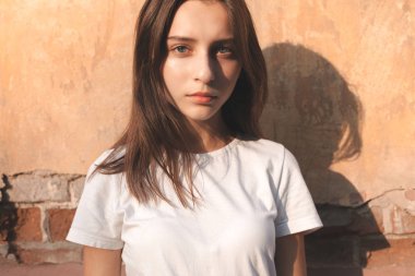 Güneş ışığında duvarın yanında duran güzel bir kadın. Yakın çekim