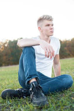 çimlerde oturan yakışıklı genç