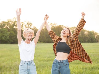 İki en iyi arkadaş sahada ayakta ve eller yükselmek.