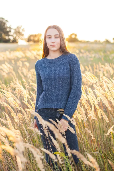 Attractive young woman stands among the spikelets