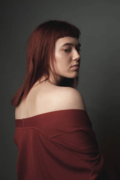 Young woman with red hair in studio