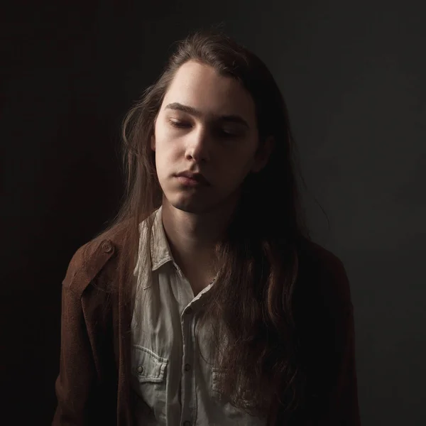 長い髪を持つ若い男のスタジオの肖像画 ローキー — ストック写真