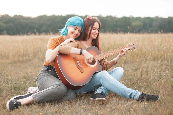 Duas Mulheres Bonitas Sentam Grama Tocam Guitarra — Fotografia de Stock