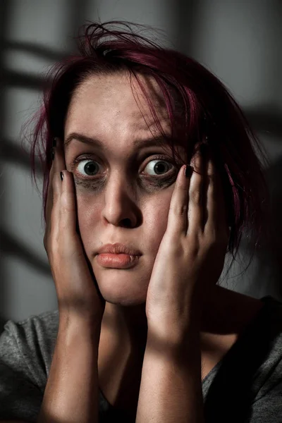 Scared woman with smeared make up in shadows