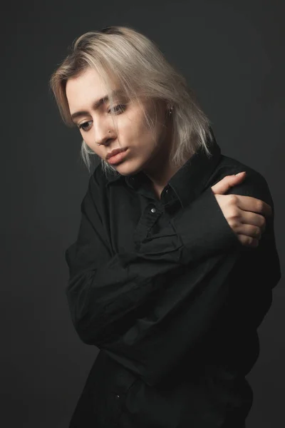 Sad young woman with black shirt on black background.