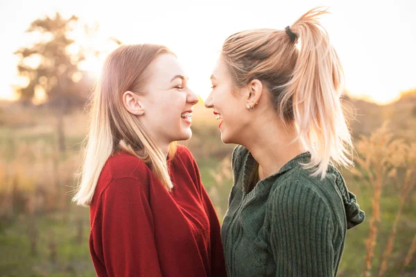 Two young women laughing outdoors at evening