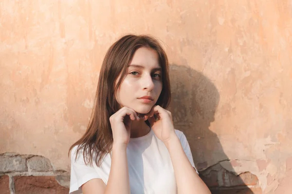 Atrakcyjna Młoda Kobieta Stoi Pobliżu Ściany Pod Słońcem — Zdjęcie stockowe