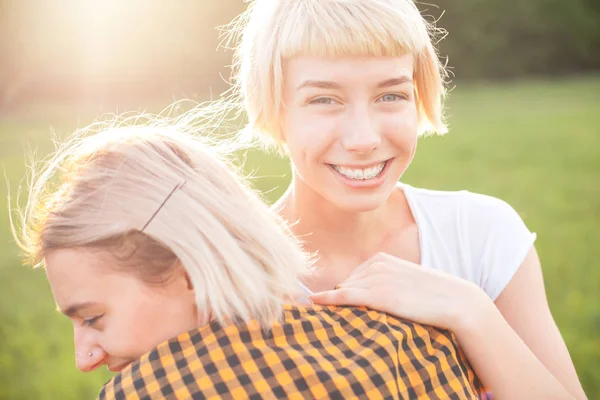 两个年轻女子在阳光下拥抱在户外 — 图库照片