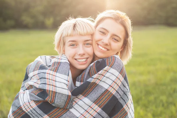 Two best friends hugging and standing on the field under sunlight