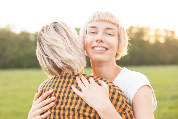 Two best friends hugging outdoors. Close up