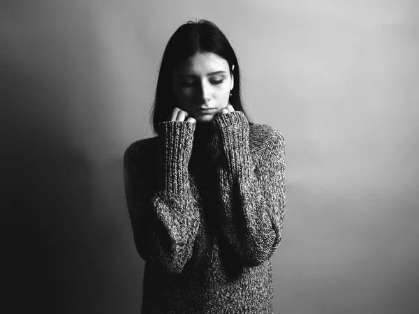 Beautiful young woman with sweater on gray background. Black and white
