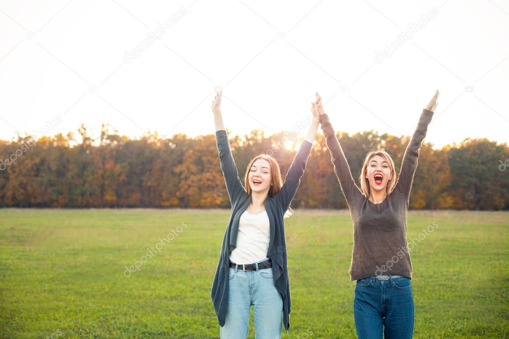 Two young women having fun on the green field