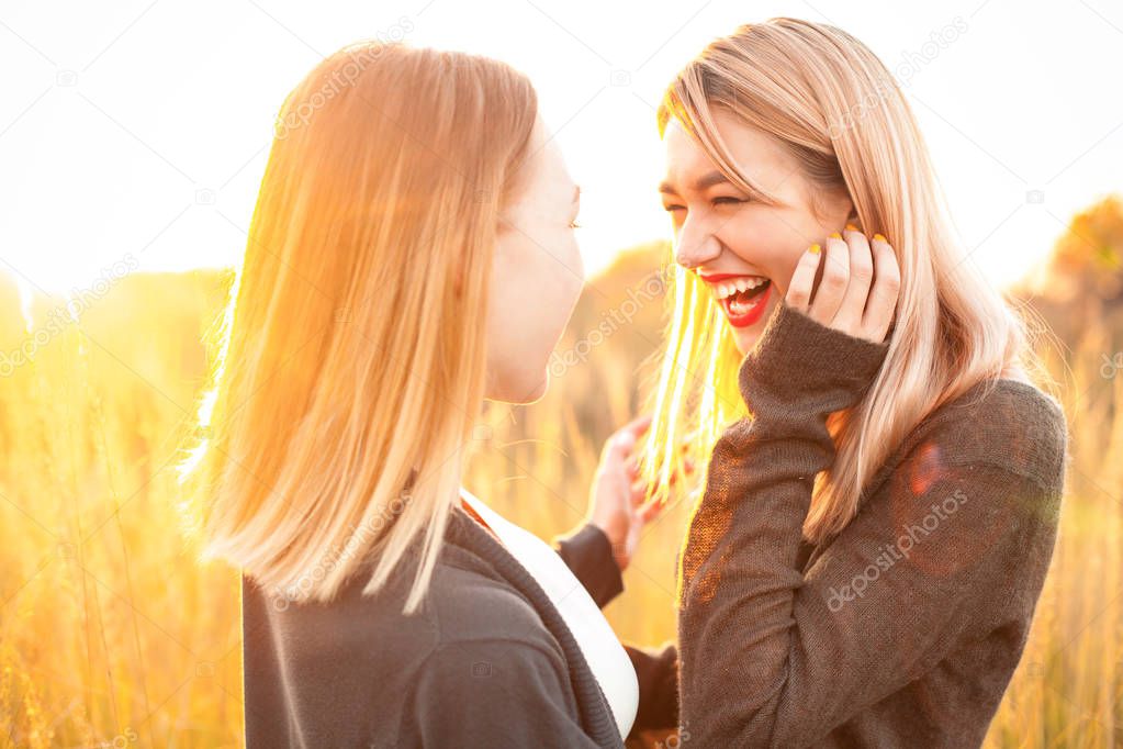 Two cheerful young woman having fun outdoors at sunset