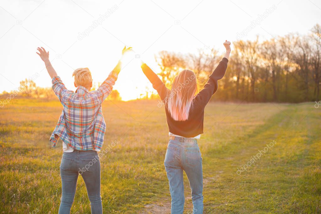 Two young women standing outdoors and looking on the sun