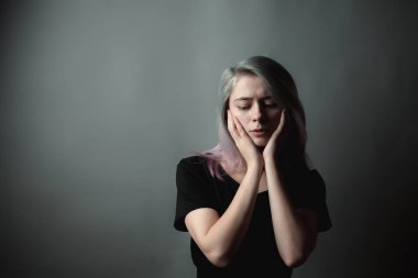 Gri arka plan üzerinde üzgün genç kadının portresi.