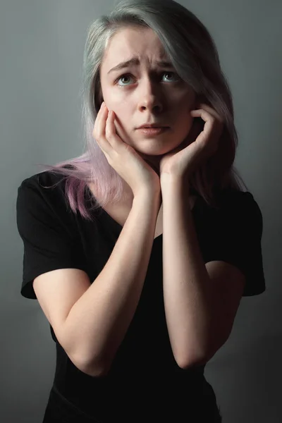 Portrait of the sad girl on gray background.