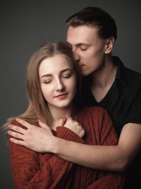 Gri arka planda sarılan neşeli çift.