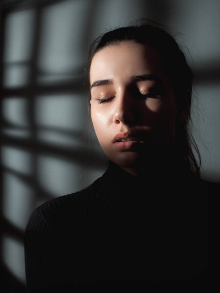 Portrait of a sad young woman in shadows.