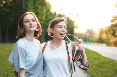 İki neşeli genç kadın gün batımında şehirde yürüyor