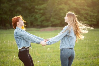 İki neşeli genç kadın güneş ışığı altında eğleniyor. En iyi dostlar
