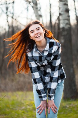 Genç bir kadın ormanda yürüyor ve gülüyor..