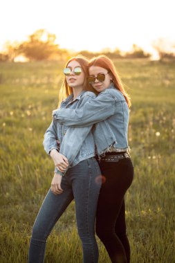 Gün batımında dışarıda birlikte duran iki genç kadın. En iyi dostlar